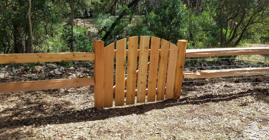 Custom picket fence integrated into a 2-rail split-rail fence design.