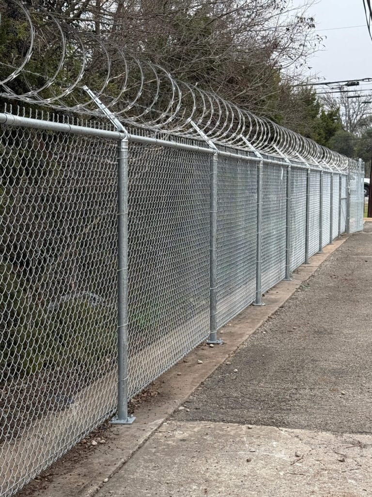 Commercial-grade chain link security fencing with barbed wire and razor ribbon.