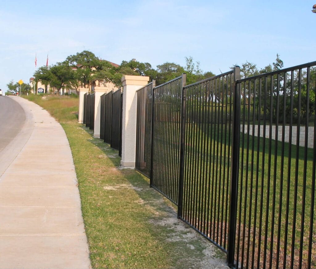 Tall ornamental fence with stone columns on a sloped grade
