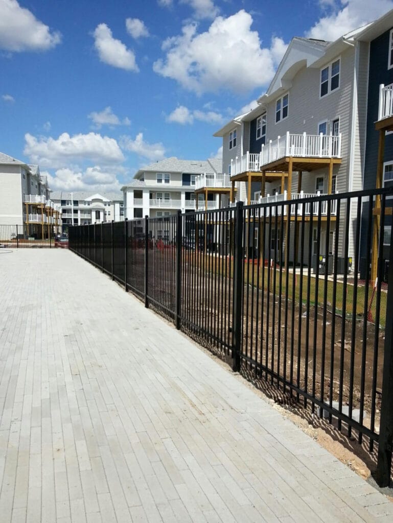 Two-rail ornamental steel fence enclosing a multi-family property