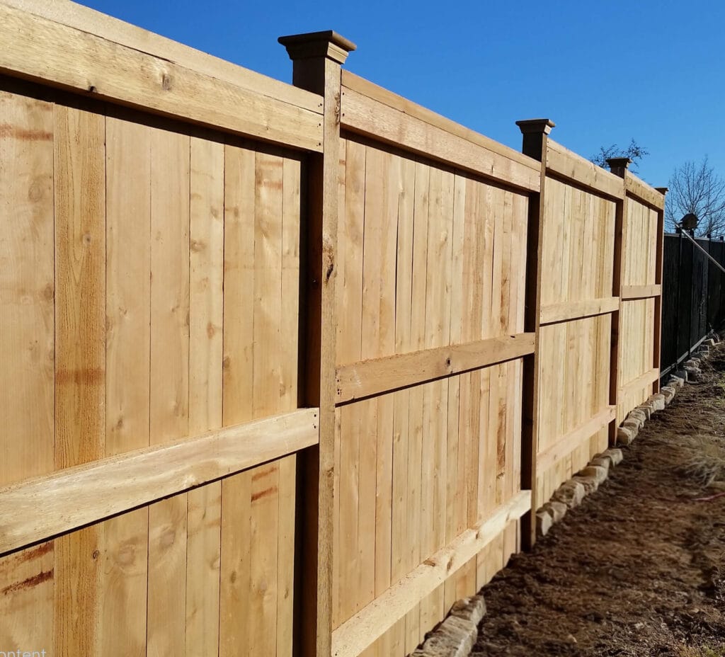 Cedar fence with post caps and stair-stepped trim for sloped terrain
