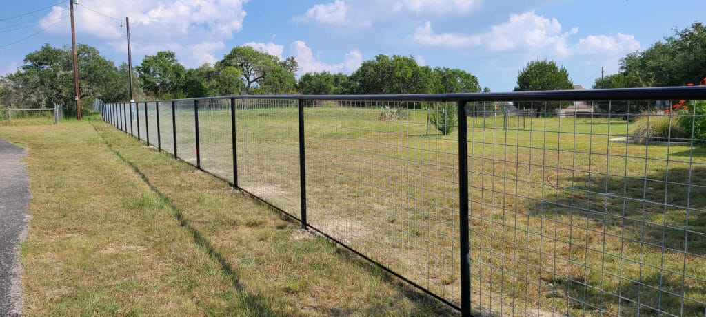 Cattle panel fence with round pipe rail and angle-iron base offering sturdy open-view perimeter.