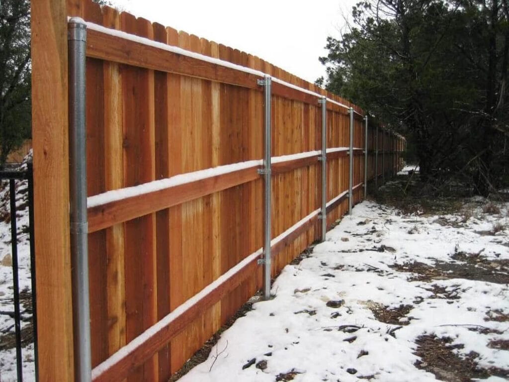 Cedar privacy fence in snow showcasing craftsmanship and natural wood beauty