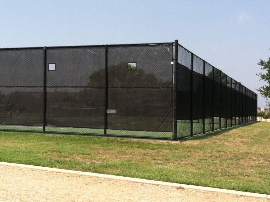 Commercial tennis court fence with attached privacy screen reducing wind and enhancing playability.