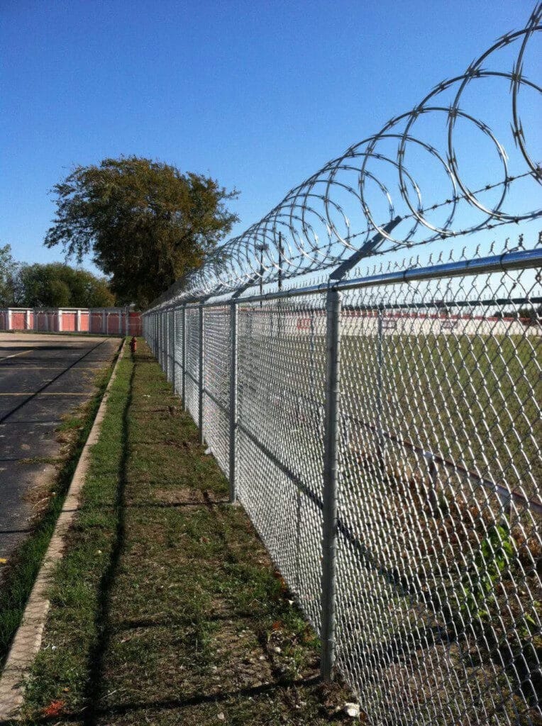 High-security chain link fence topped with razor ribbon guarding Central Texas storage yard.