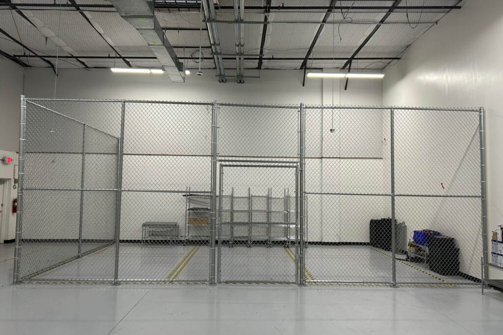 Twelve-foot interior chain link cage for secure equipment storage inside warehouse facility.