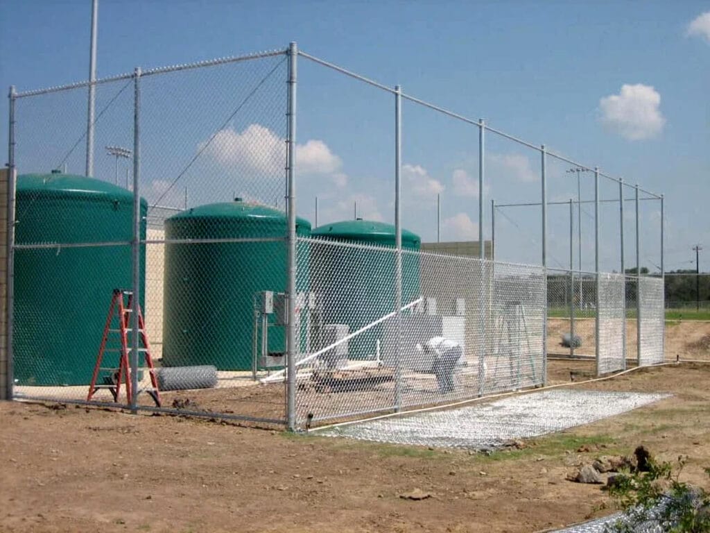 Tall 10-foot utility chain link enclosure securing service and equipment zones.