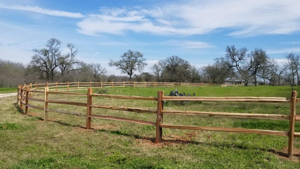 Three-rail cedar split-rail fence blending naturally into Hill Country landscape.